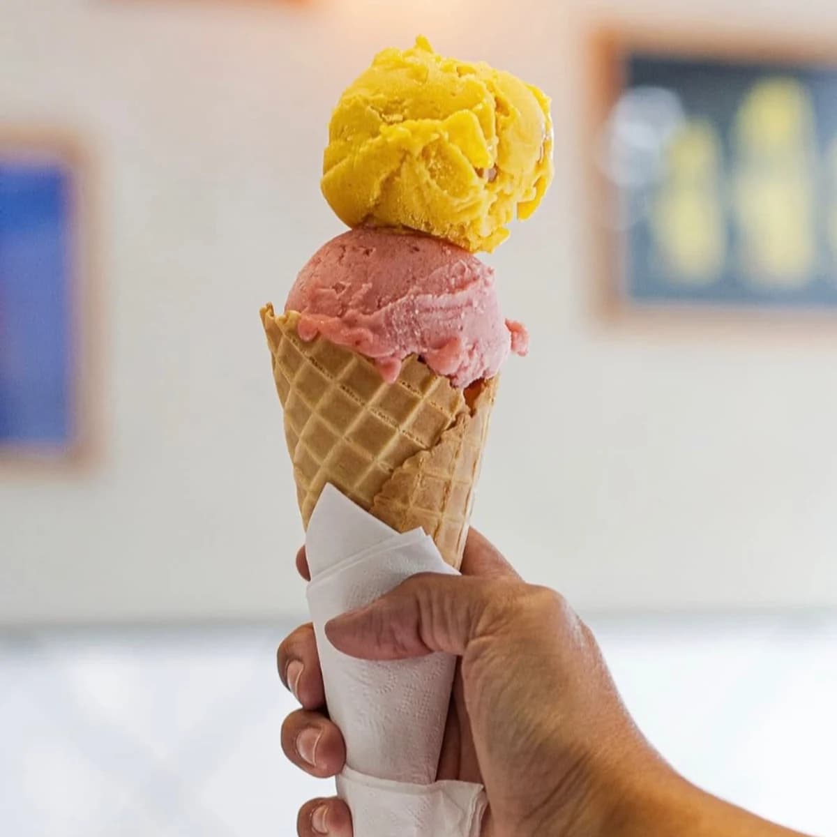 A two-scoop A Pagnotta gelato cone held in hand